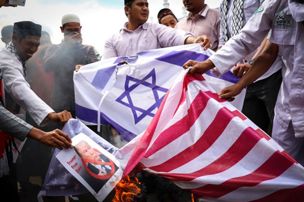 Muslim men burn Israeli and United States flags during a protest against former US president Donald Trump's decision to recognize Jerusalem as Israel's capital, in Banda Aceh, Indonesia, December 8, 2017.