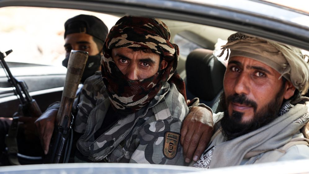 Fighters from Bedouin tribes ride in a car along a road in al-Mazraa village in Syria's southern Sweida governorate, as clashes with Druze gunmen continue on July 18, 2025. 