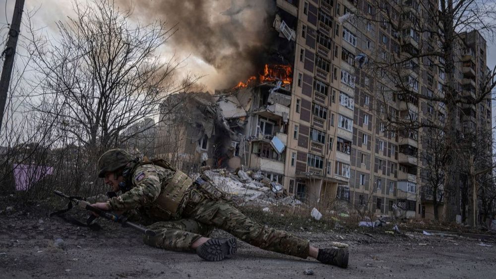 "Un soldat ukrainien s'abrite devant un bâtiment en feu touché par une frappe aérienne russe à Avdiivka, Ukraine (archives)"
