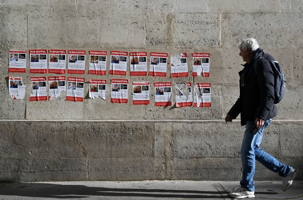 Un homme passe devant des pancartes montrant des Israéliens retenus en otages par le Hamas, dans le centre de Paris
