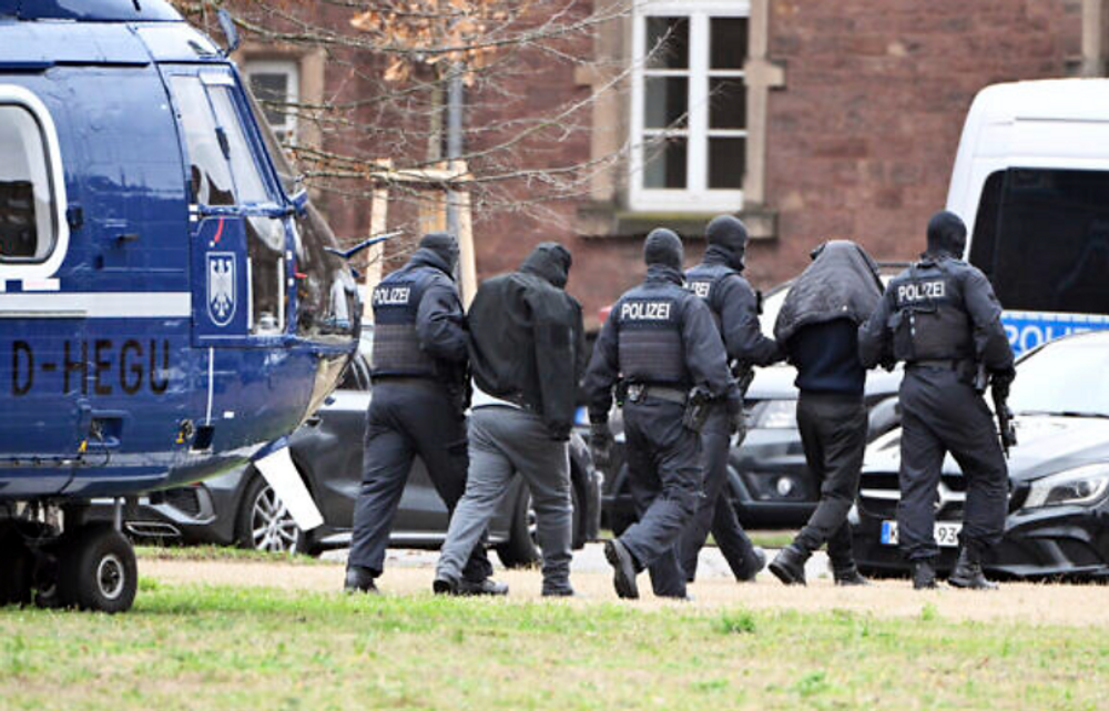 Deux suspects sont emmenés d'un hélicoptère à une voiture par des policiers dans un héliport de Karlsruhe, en Allemagne, le 15 décembre 2023.