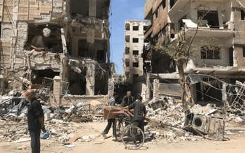 Des personnes se tiennent devant des bâtiments endommagés, dans la ville de Douma, site d'une attaque présumée aux armes chimiques, près de Damas, en Syrie