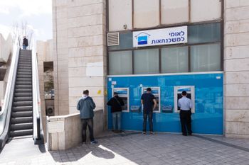 Israelis cashe out money from an ATM machine in Jerusalem on February 22, 2018.