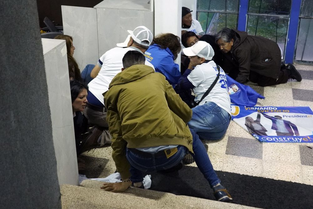 People take cover after shots were fired at the end of a campaign rally fpr presidential cadidate Fernando Villavicencio in Quito, Ecuador