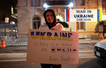 A man holds a banner after a vigil to mark one year since Russia's invasion of Ukraine, outside the Russian consulate in New York, United States.