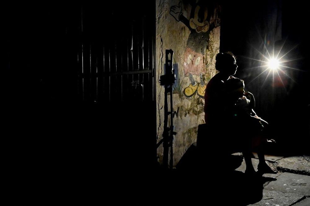 A woman with a child sits outside her house during a power cut in Colombo, Sri Lanka, on March 30, 2022.