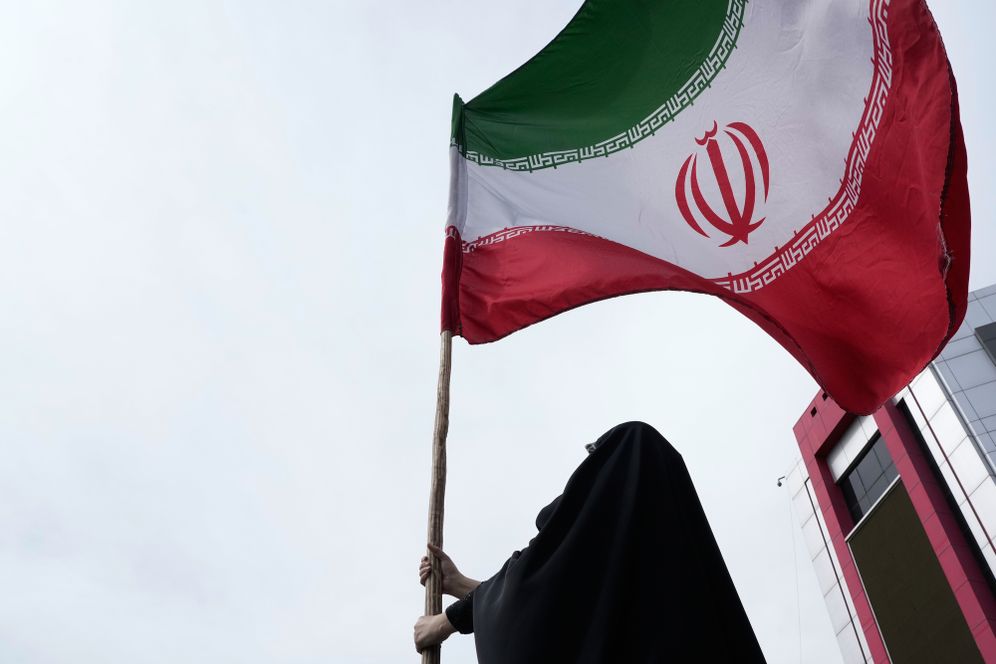 Une femme brandit un drapeau iranien lors d'une campagne progouvernementale dans le centre de Téhéran, en Iran, le samedi 25 avril 2026.