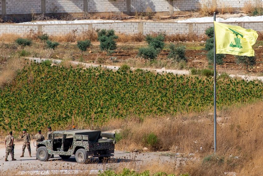 Lebanese soldiers next to a Hezbollah flag patrol in the southern Lebanese village of Aitaroun, on the Israel-Lebanon border, Israel, Tuesday, Aug. 27, 2019.