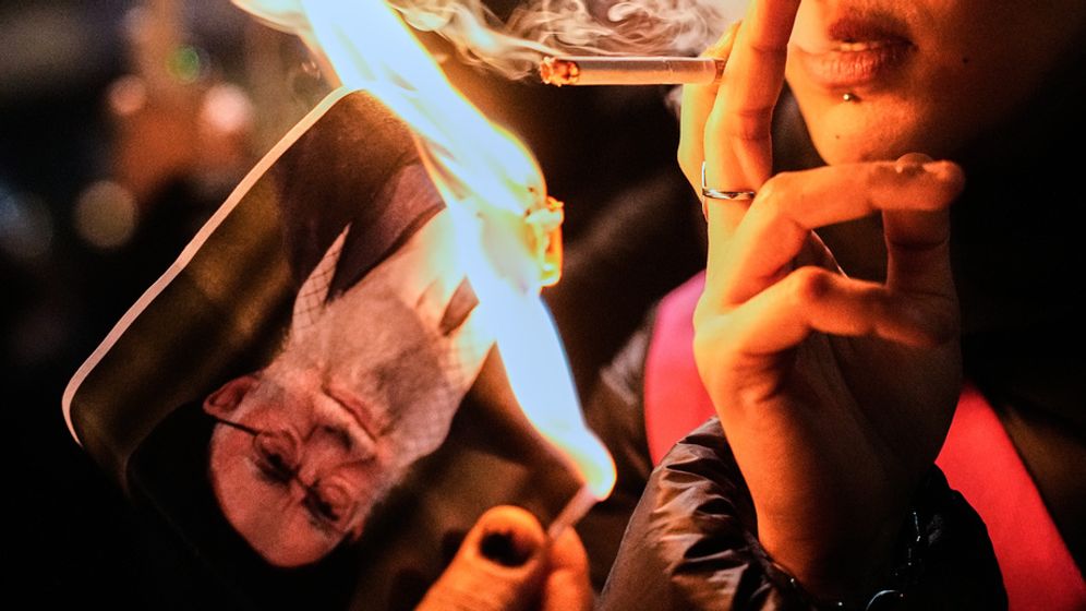 ASOCIATED PRESS מפגינה שורפת את תמונתו של המנהיג העליון של איראן, עלי חמינאי