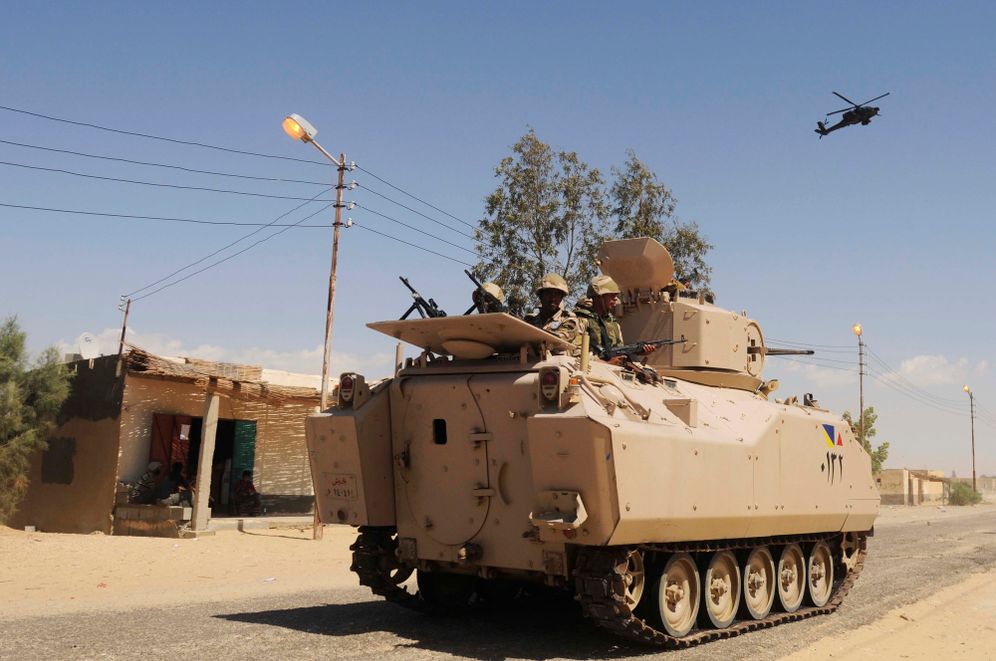 Egyptian Army soldiers patrol in an armored vehicle backed by a helicopter gunship during a sweep through villages in Sheikh Zuweyid, north Sinai, Egypt