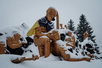 A memorial statue with the Ukrainian flag tied across the shoulders of one of the statues is covered by snow in Chasiv Yar, Ukraine.