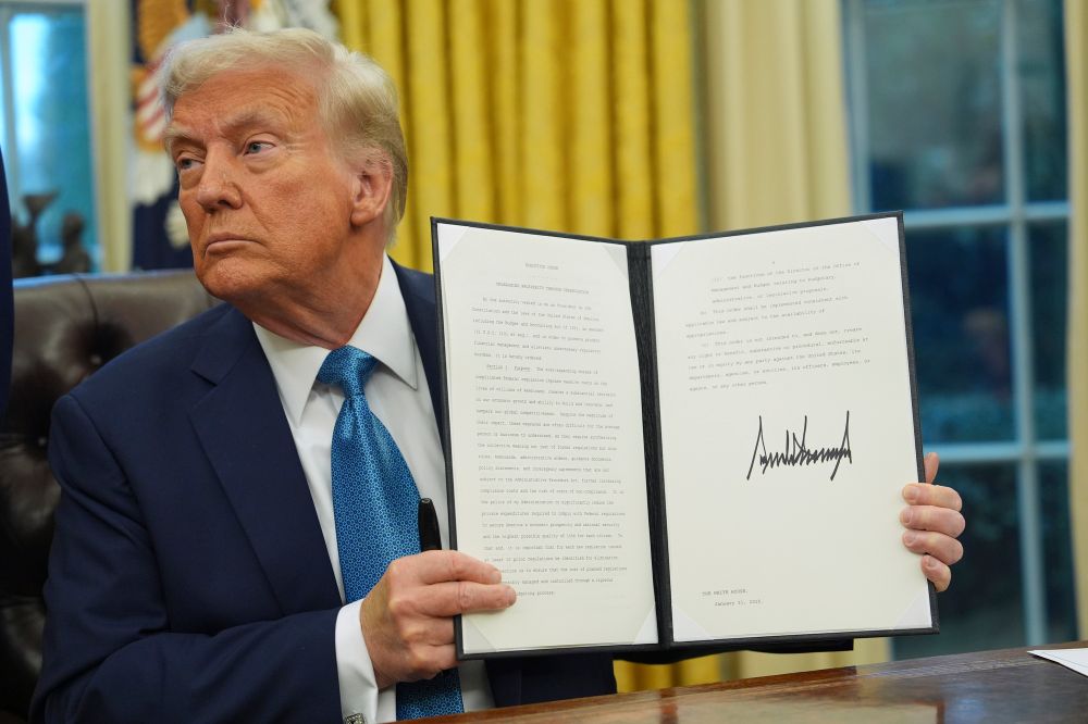President Donald Trump speaks to reporters as he signs executive orders in the Oval Office of the White House in Washington, DC