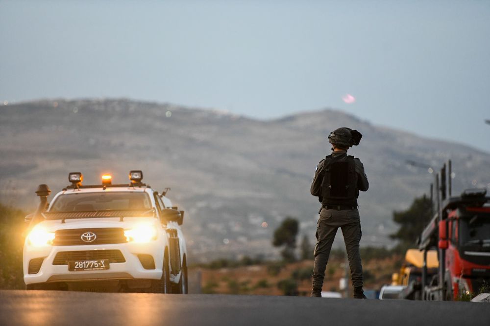 Des soldats et des policiers israéliens inspectent les lieux de la fusillade au carrefour de Tapuah, au sud de la ville de Naplouse en Cisjordanie, le 2 mai 2021