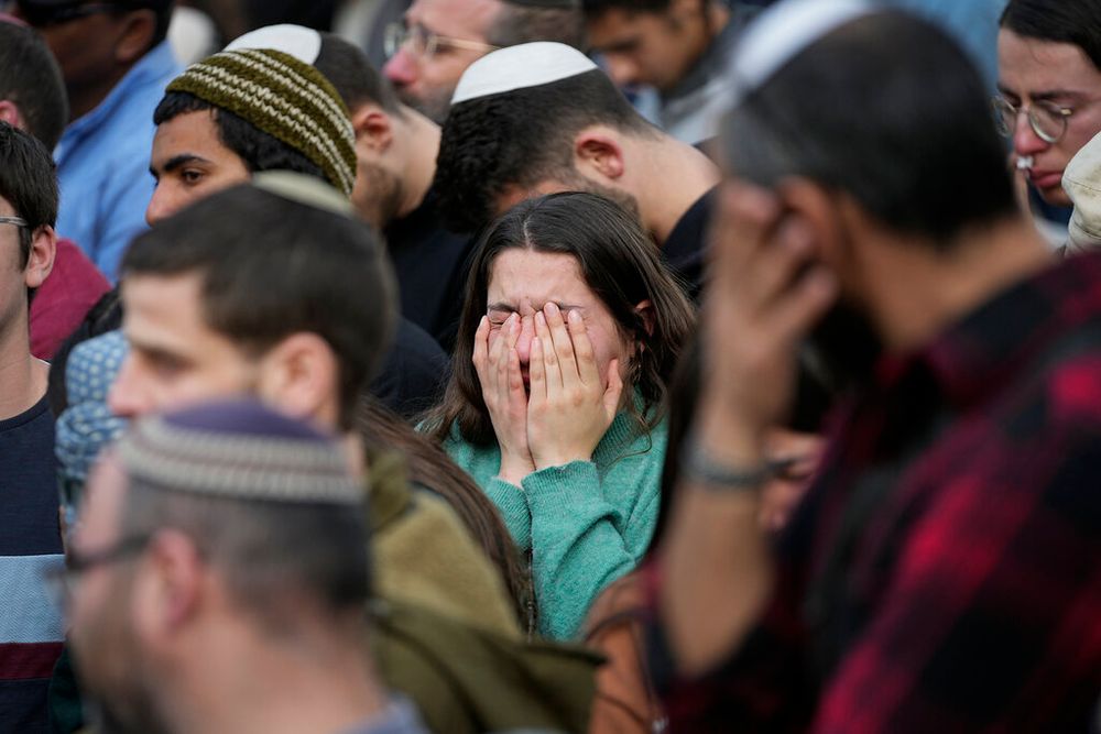 Mourners react during the funeral of two brothers murdered in the West Bank, at Israel's national cemetery in Jerusalem.