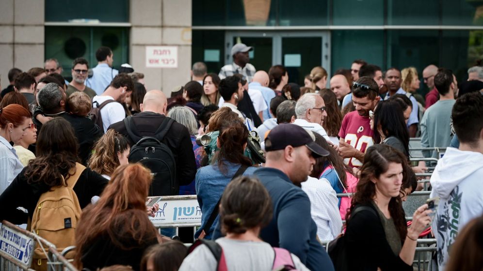 People stand in line outside a government office (the people photographed are not related to the article).