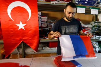 An employee of a flag-making factory folds a Russian flag as a Turkish flag adorns the display at left, in Istanbul, Turkey, August 9, 2016.