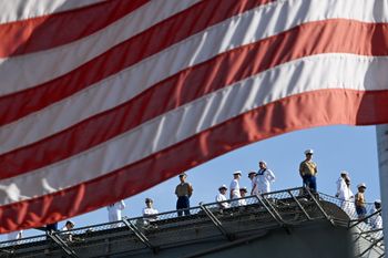 An American flag frames Marines and Navy sailors from the USS Bataan in New York City, US