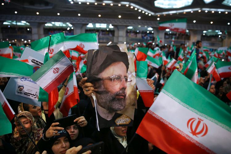 Supporters of hard-line cleric Ebrahim Raisi hold his photo and wave their country's flag in Tehran, Iran.