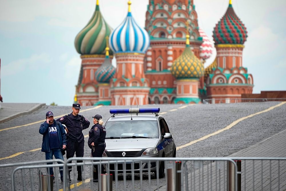 Police officers stand next to their car in an empty Red Square in Moscow, Russia.