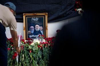 رجل يضع الزهور بالقرب من صورة الرئيس الإيراني إبراهيم رئيسي ومرافقيه في نصب تذكاري مؤقت في السفارة الإيرانية في موسكو، روسيا، الاثنين 20 مايو 2024.