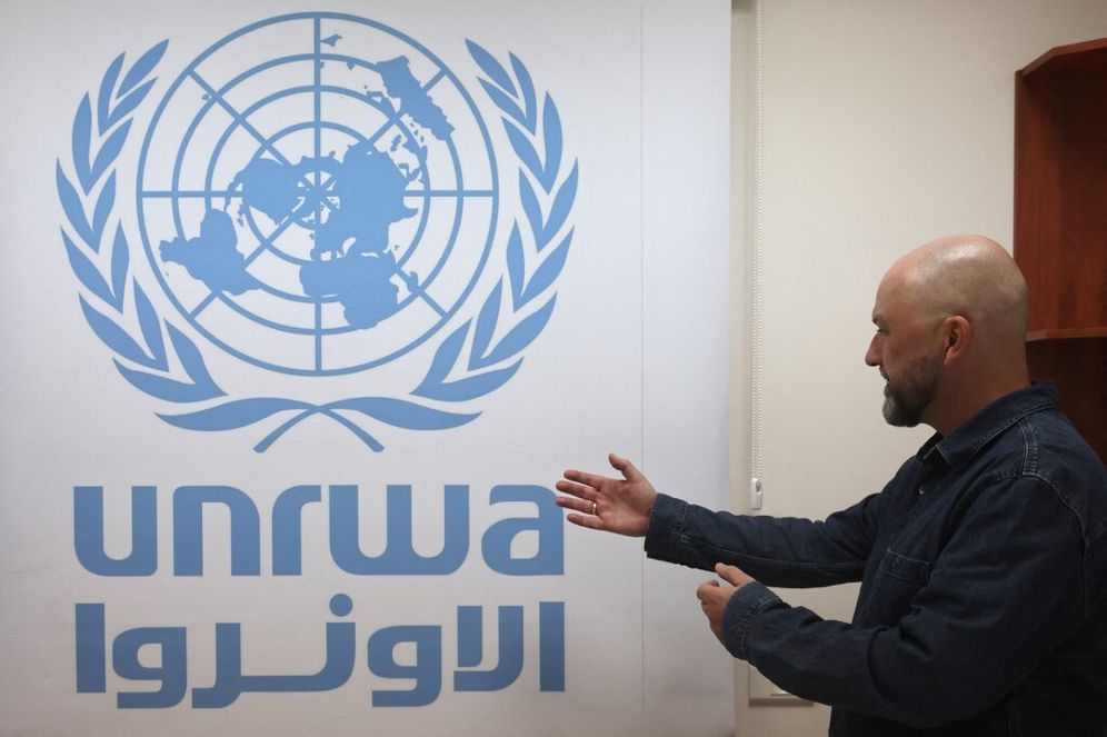 Le porte-parole de l'UNRWA, Jonathan Fowler, montre le logo de l'agence dans son bureau de Cisjordanie à Jérusalem, le 29 octobre 2024