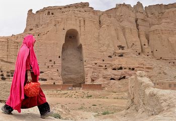 A Hazara Afghan woman walks past the ruins of the ancient Buddha statues that once stood in the city of Bamiyan, Afghanistan.