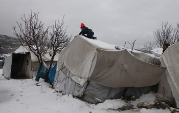 A young Syrian boy clears the snow covering a tent at a camp for internally displaced people in the Idlib governorate of northwestern Syria, on January 23, 2022, as winter storms hit the area.