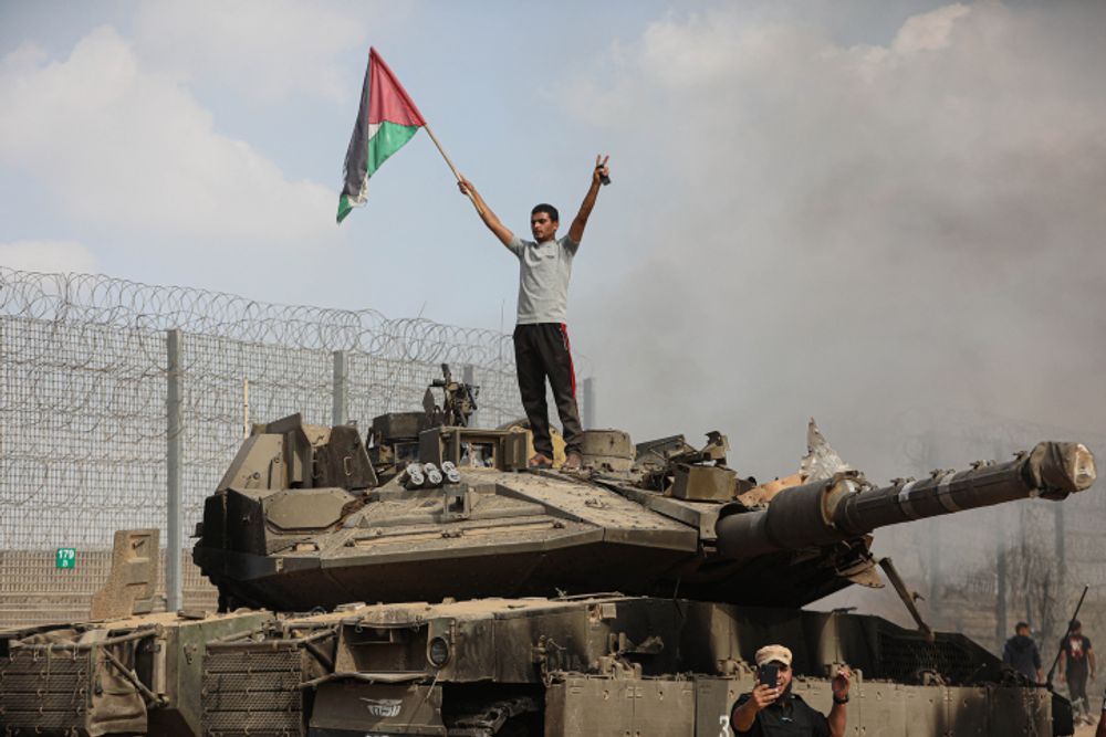 Hamas terrorists take control of an Israeli tank on the border fence, October 7, 2023.