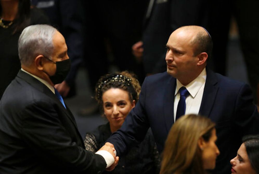 (AP Photo/Ariel Schalit) ئيس الوزراء الإسرائيلي الجديد نفتالي بينيت يصافح رئيس الوزراء المنتهية ولايته بنيامين نتنياهو خلال جلسة للكنيست في القدس يوم الأحد ، 13 يونيو ، 2021.