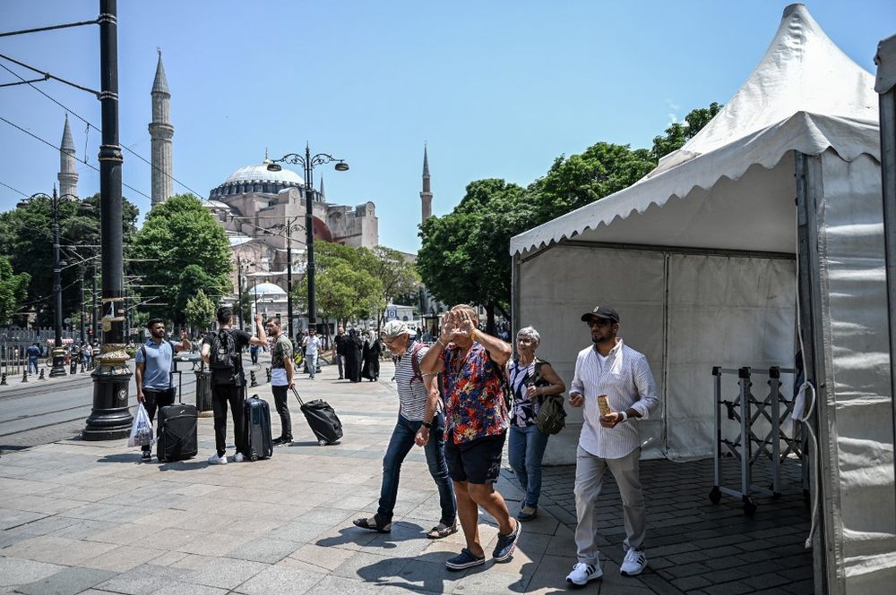 Tourists pass through a police checkpoint in Istanbul as the Blue Mosque and Hagia Sophia Mosque are surrounded by a police fence for security reasons, on June 14, 2022.