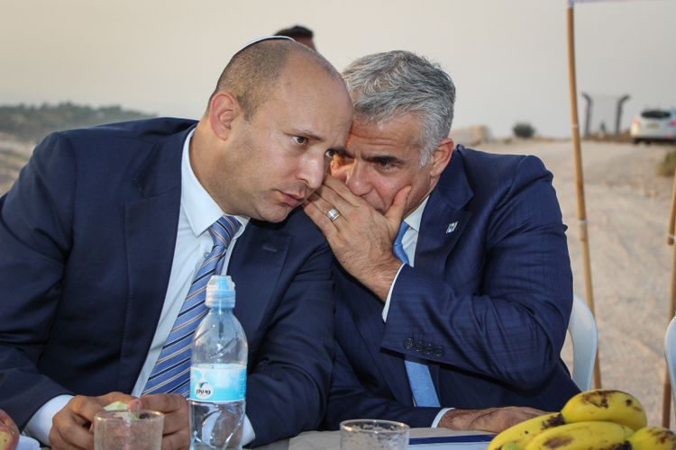 Knesset Member Yair Lapid (right) whispers to then-Education Minister Naftali Bennett in the Netiv Avot neighborhood in Gush Etzion, on July 23, 2017.