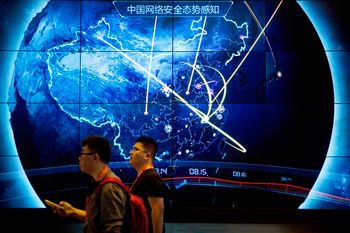Attendees walk past an electronic display showing recent cyberattacks in Beijing, China.