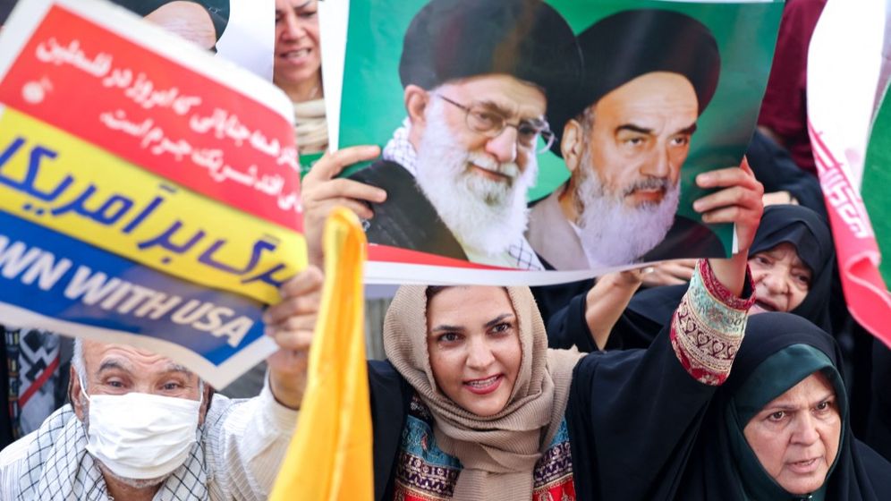 امرأة في طهران تحمل لافتة عليها صور خامنئي، في مظاهرة مؤيدة للنظام بعد الحرب