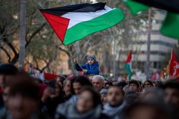 صبي يلوح بالعلم الفلسطيني بينما يسير المتظاهرون خلال احتجاج لدعم الفلسطينيين ويطالبون بوقف فوري لإطلاق النار في غزة، في برشلونة، إسبانيا، في 20 يناير 2024