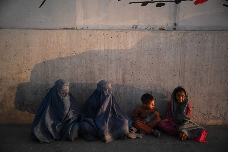Burqa-clad Afghan women along with children sit on a street in Kabul, Afghanistan, on July 19, 2022.