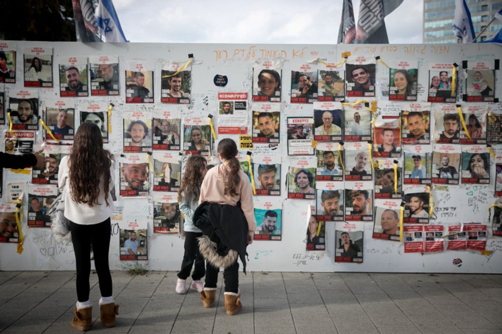 People walk by photographs of civilians held hostage by Hamas terrorists in Gaza, at "Hostage Square" in Tel Aviv, January 13, 2024