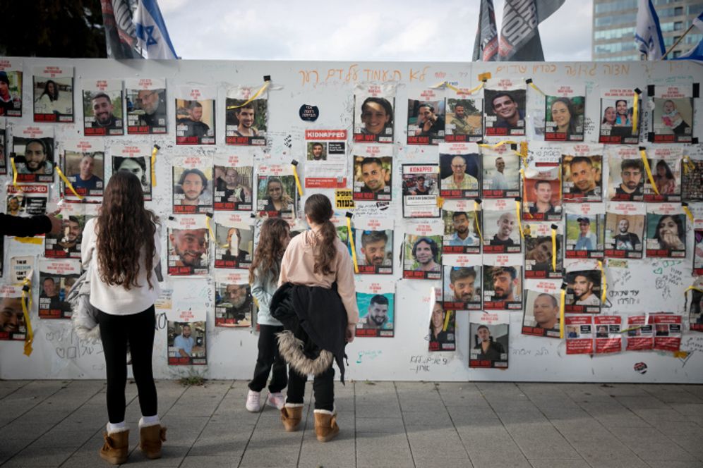 Miriam Alster/FLASH90 People walk by photographs of civilians held hostage by Hamas terrorists in Gaza, at "Hostage Square" in Tel Aviv, January 13, 2024