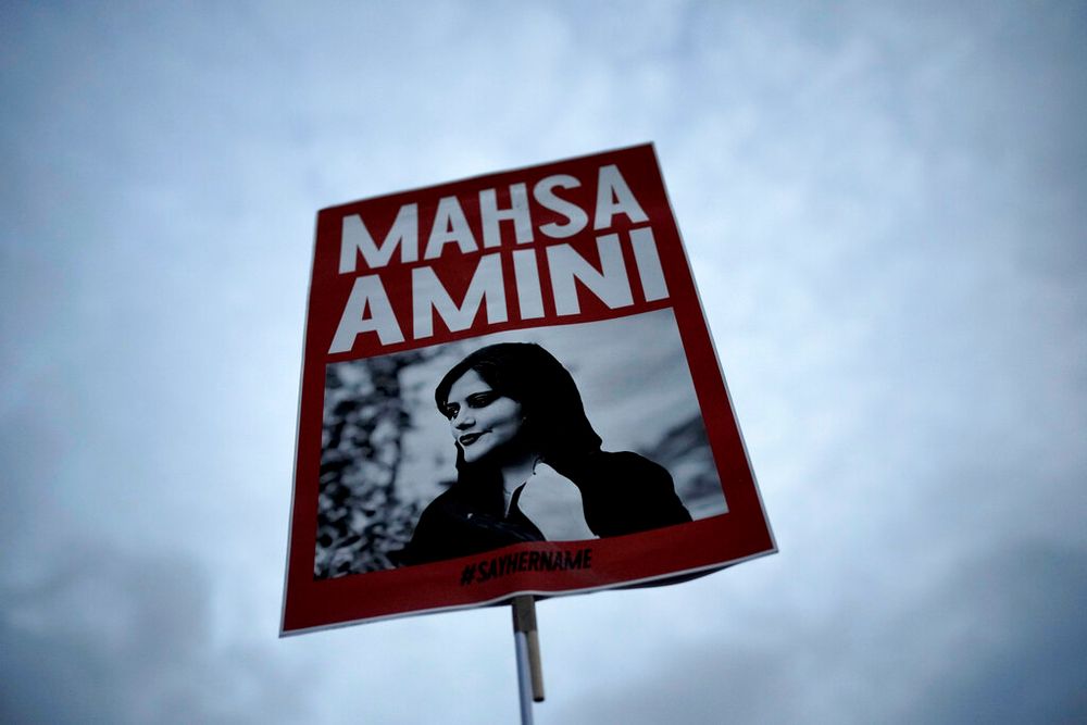A woman holds a placard with a picture of Iranian Mahsa Amini as she attends a protest against her death, in Berlin, Germany, September 28, 2022