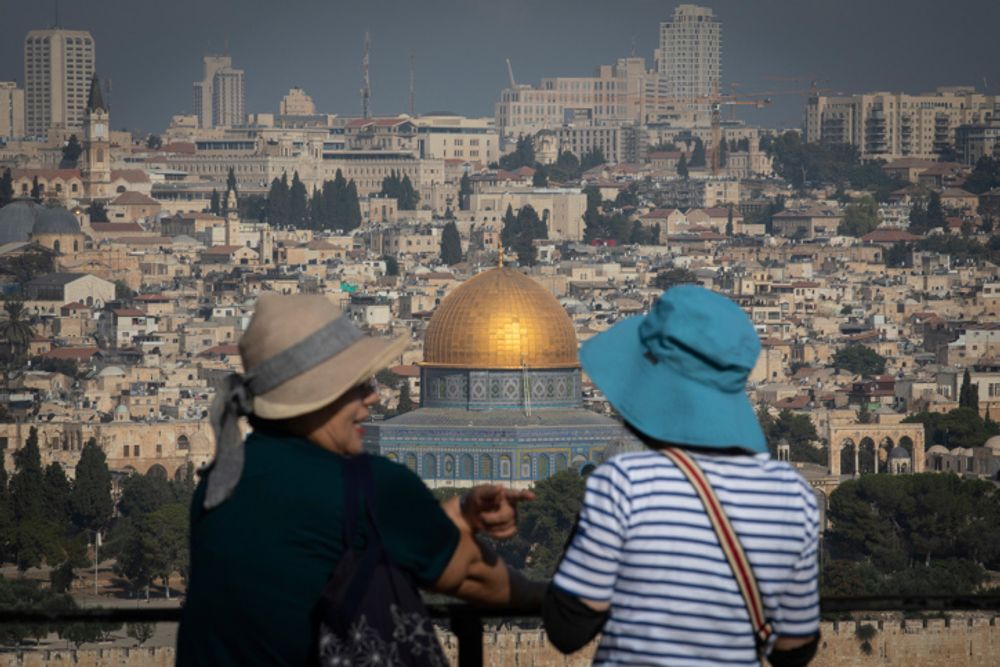 Tourists look at a view of the Old City of Jerusalem from the Mount of Olives, on August 5, 2019.