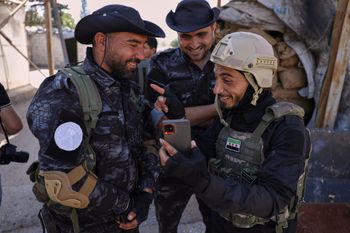 A member of the government security forces, right, laughs with fighters from the Kurdish-led Syrian Democratic Forces during a prisoner exchange in the Sheikh Maqsoud neighborhood of Aleppo, Syria, Monday, June 2, 2025.