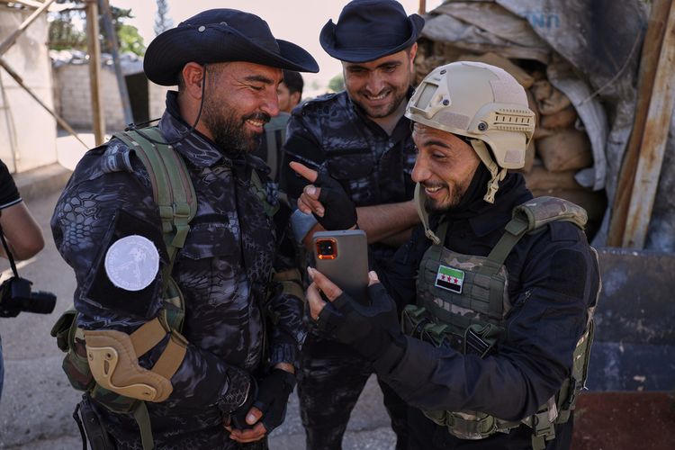 A member of the government security forces, right, laughs with fighters from the Kurdish-led Syrian Democratic Forces during a prisoner exchange in the Sheikh Maqsoud neighborhood of Aleppo, Syria, Monday, June 2, 2025.