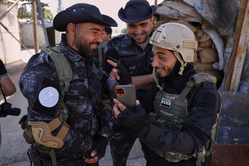 A member of the government security forces, right, laughs with fighters from the Kurdish-led Syrian Democratic Forces during a prisoner exchange in the Sheikh Maqsoud neighborhood of Aleppo, Syria, Monday, June 2, 2025. 
