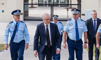 Le Premier ministre australien Anthony Albanese marche aux côtés de policiers après avoir déposé des fleurs le 15 décembre 2025, sur les lieux d'une attaque terroriste visant la fête de Hanouka.