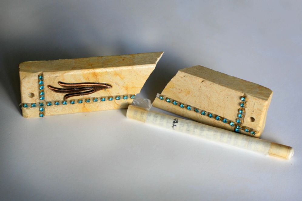 Illustration - A broken mezuzah with the piece of parchment inscribed with specified Hebrew verses from the Torah.