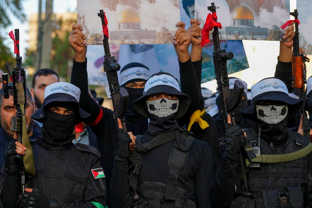 Masked militants from the military wing of Hamas march with their weapons and wave their flags as well as Palestinian flags, in Gaza City, the Gaza Strip.