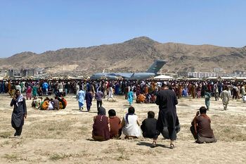 Hundreds of people gather near a United States Air Force C-17 transport plane at a perimeter at the international airport in Kabul, Afghanistan, August 16, 2021.