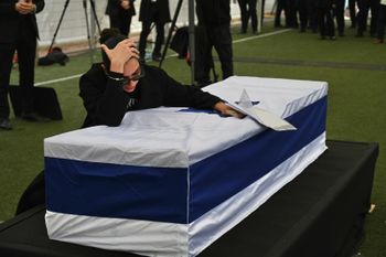 Ran Gvili's sister is leaning over his coffin.
