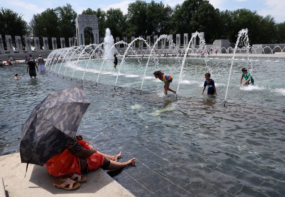 Visitors and tourists to the World War II Memorial seek relief from the hot weather in the memorial's fountain on July 03, 2023 in Washington, DC, U.S.