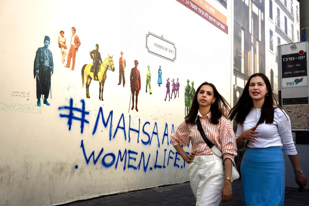 Israeli women in Jerusalem stroll past graffiti that reads '#MahsaAmini - women.life.freedom' in solidarity with Iran's anti-regime protest movement.