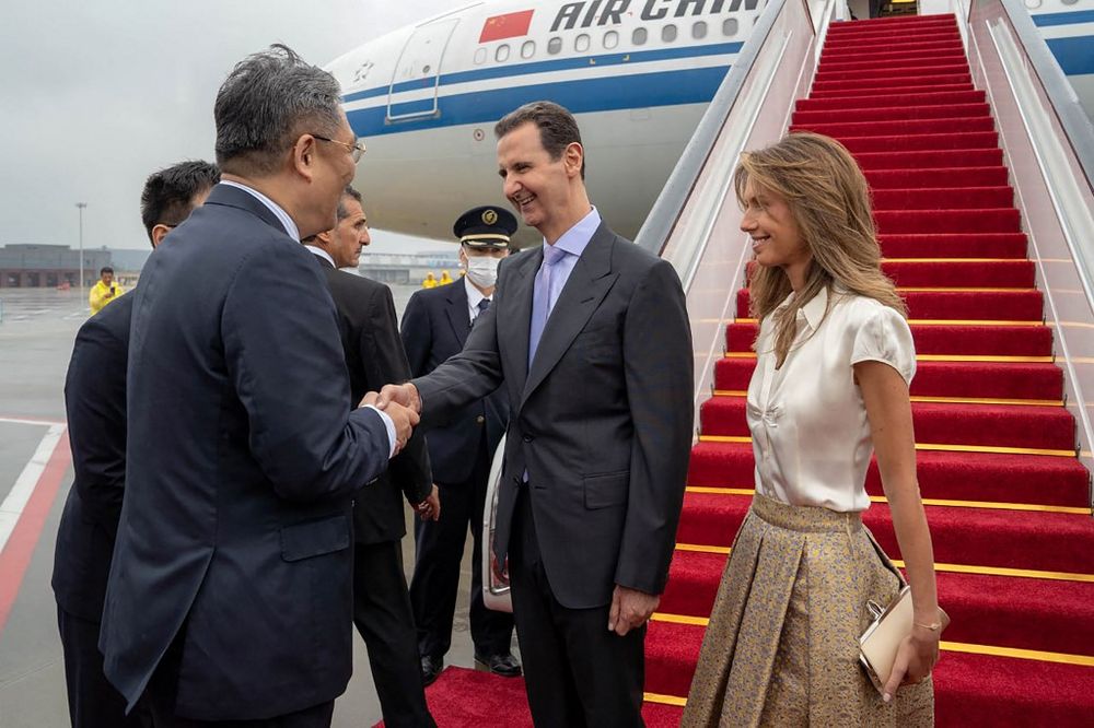 A handout picture released by the official Syrian Arab News Agency (SANA) shows Syria's President Bashar al-Assad (C) and First Lady Asma al-Assad being welcomed upon their arrival at the airport in Beijing, China.